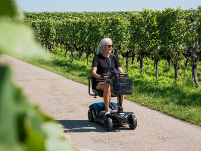 women drives scooter in the vineyard